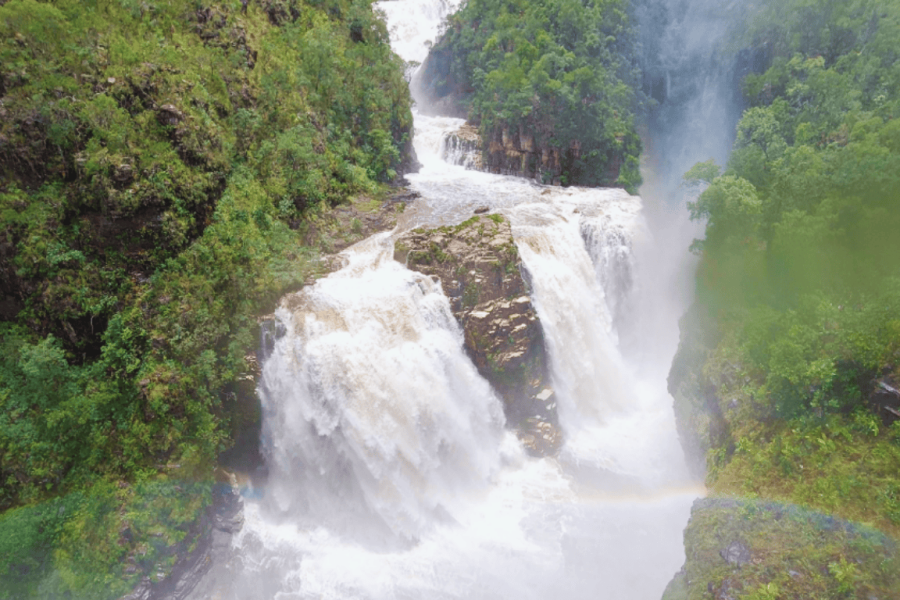 Aerial view of one of the Couros Waterfalls, with a large volume of water flowing between canyons and the savannah vegetation of Chapada dos Veadeiros.