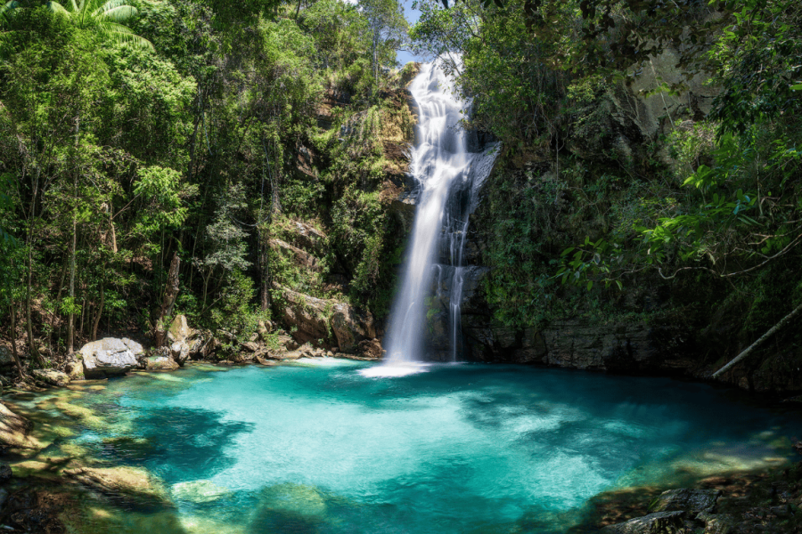 Santa Bárbara Waterfall in Cavalcante, Goiás, with a cascade surrounded by cerrado vegetation and a turquoise-blue natural pool.