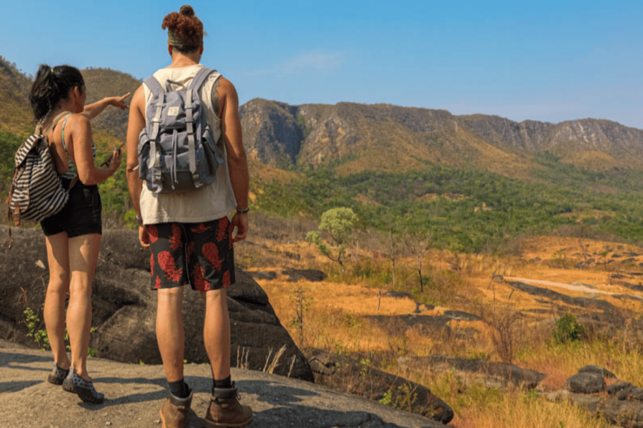 Travelling couple at a viewpoint in Chapada dos Veadeiros, overlooking the Brazilian Cerrado with mountains and landscapes in the background.